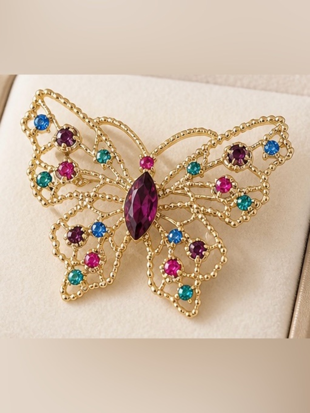 Dodds filigree butterfly brooch featuring a large amethyst-colored center stone